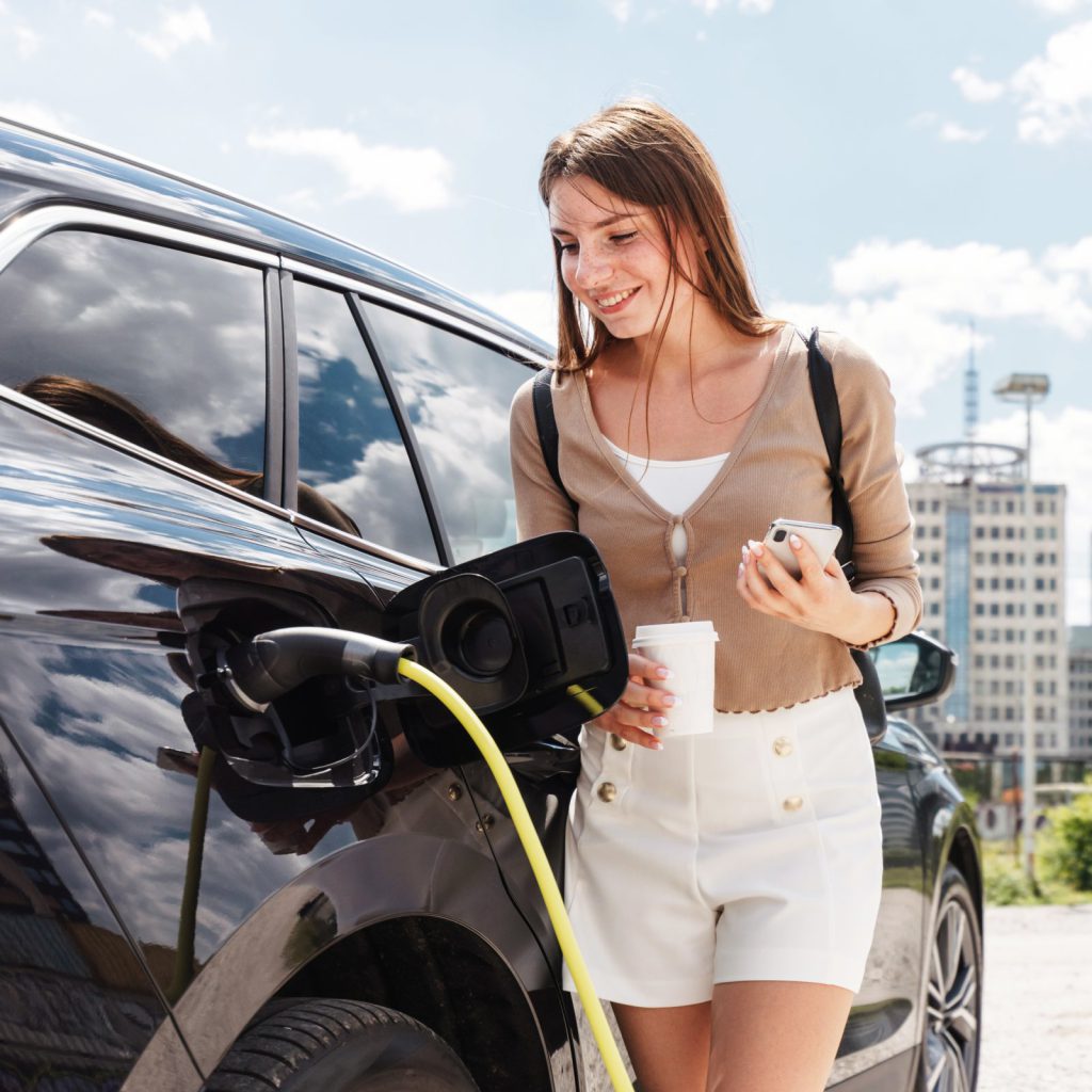 Woman checking her phone while charging an electric car